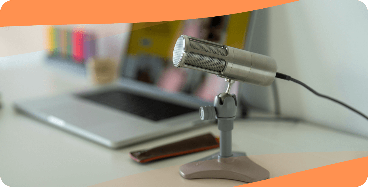 A USB microphone on a desk with a computer in the background